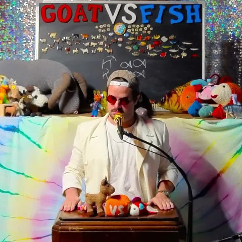 A Guest Sermonizer at the pulpit under the GOAT VS FISH board